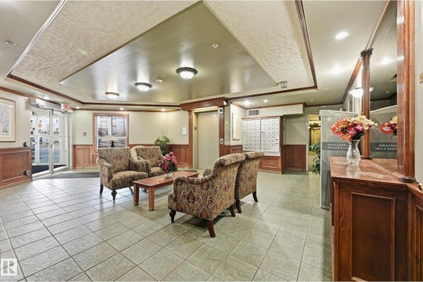 Lobby seating area with patterned chairs, coffee table, and mailboxes. - #429 9704 174 St Nw, Edmonton