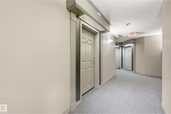 Interior hallway with carpeted floor and multiple apartment doors. - #429 9704 174 St Nw, Edmonton