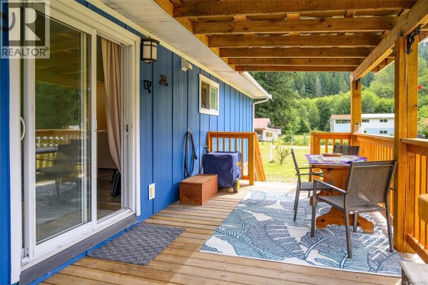 Living area with green walls, dining table, chairs, and armchair. - 429 Community Rd, Sayward