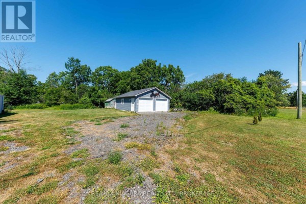 A grey detached double garage with two garage doors is visible from a grassy field. - 429 Delaware Avenue, Fort Erie
