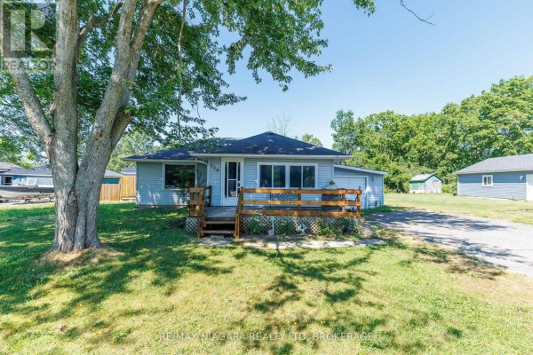 Front view of a light blue bungalow with a wooden deck and mature tree. - 429 Delaware Avenue, Fort Erie
