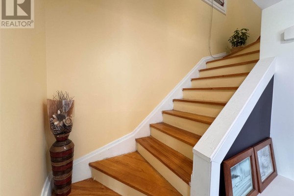 Wooden staircase with light yellow walls and a decorative vase on the left. - 429 Grenfell Crescent, Labrador City