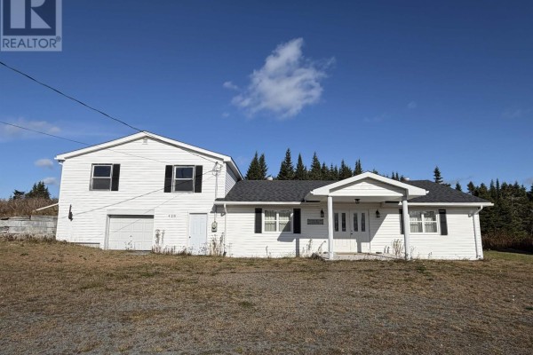 Side view of the house with a sloped yard and shrubs - 429 Highway 7, Ecum Secum