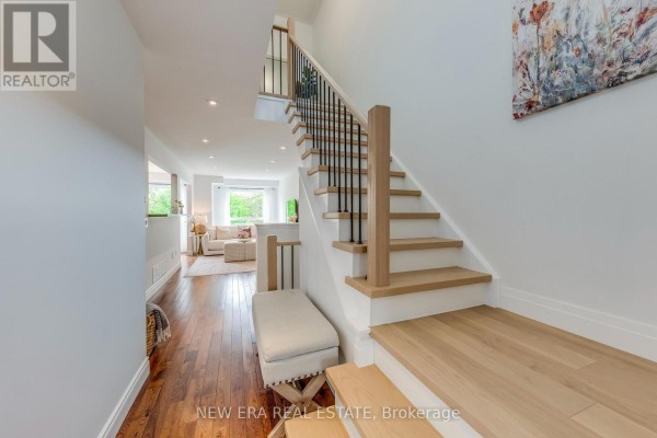 Primary bedroom with a king bed, walk-in closet, ceiling fan, and wooden floors. - 43 - 7284 Bellshire Gate, Mississauga