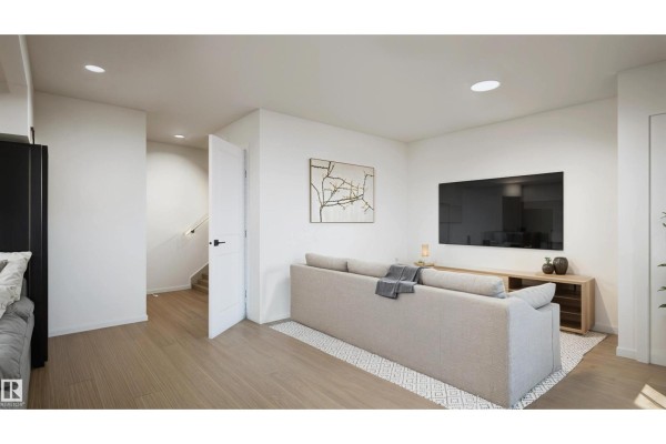 Open-concept living area with a sofa, television, and stairs leading to another level. - #43 4004 Savaryn Dr Sw, Edmonton
