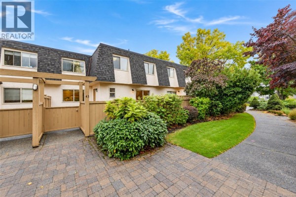 Front exterior of townhouse complex with paved walkway and landscaping under a blue sky. - 43 4061 Larchwood Dr, Saanich