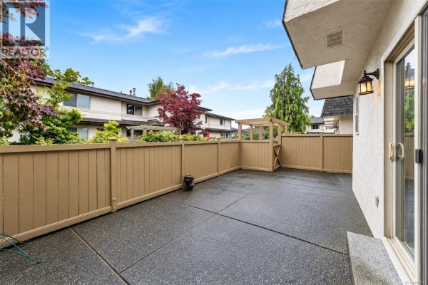 Paved patio area with wooden fence and sliding glass door leading to the townhouse. - 43 4061 Larchwood Dr, Saanich