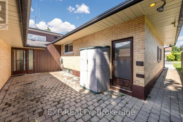 Side yard patio area with brick pavers, a storage shed, and two doors. - 43 Amelia Street S, Barrie