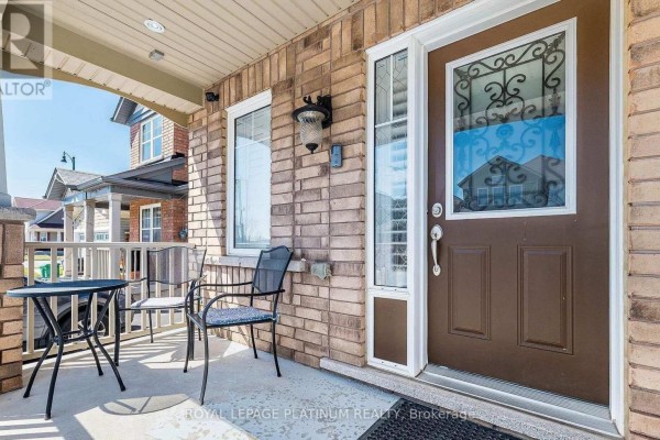 Close-up of the covered front porch with a small table, two chairs, and the brown front door. - 43 Arkwright Drive, Brampton