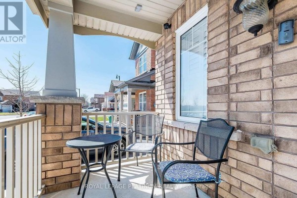 View of the covered front porch with two chairs, a small table, and brick exterior walls. - 43 Arkwright Drive, Brampton