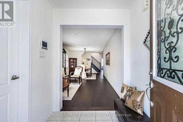 View from the entryway through an archway into a long hallway leading to a living and dining area. - 43 Arkwright Drive, Brampton