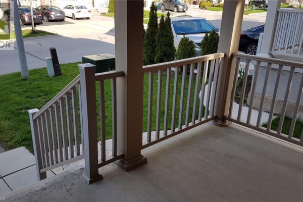 View of the porch and front stairs with a concrete floor and beige railings, facing the street. - 43 Armstrong Avenue, Cambridge