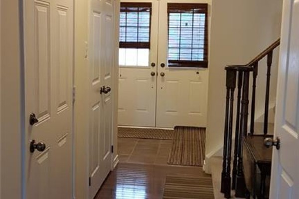 Interior view of a foyer with two white doors, tile flooring, and a staircase with dark wood railings. - 43 Armstrong Avenue, Cambridge
