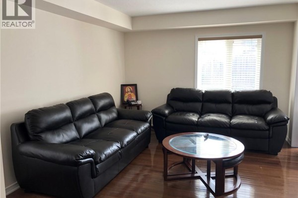 Living room with two black leather sofas, a round wood coffee table with glass top, and hardwood floors. - 43 Armstrong Avenue, Cambridge