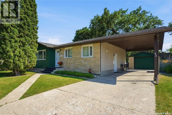Side view of the bungalow showing the driveway, carport, and garage door. - 43 Columbia Drive, Saskatoon