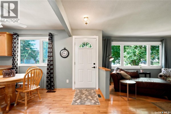 Interior view showing a dining area, kitchen cabinets, white front door, and living room. - 43 Columbia Drive, Saskatoon
