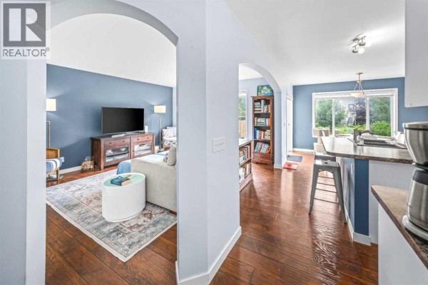 Interior view of a living room and kitchen with blue walls and hardwood floors. - 43 Cougar Ridge Bay Sw, Calgary