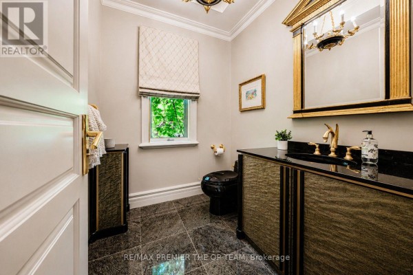 Powder room with a dark toilet, black granite vanity, gold fixtures, and marble tile floors. - 43 Cowan Drive, Vaughan