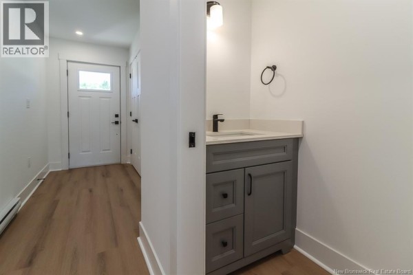 Powder room with a grey vanity, white countertop, and a black faucet next to the entrance. - 43 Downsview Drive, Saint John