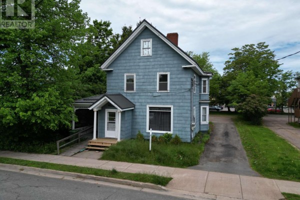 Side view of the light blue house with a gray metal roof, showing bay windows and dormers. - 43 Duke Street, Truro