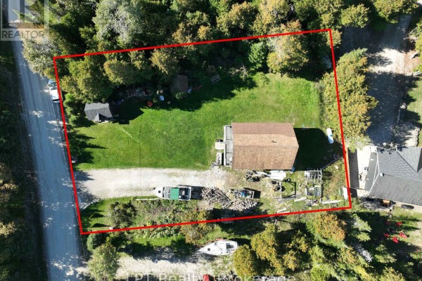 Overhead drone shot of the property, highlighting the house, cleared yard, and surrounding wooded area. - 43 Henwood Street, Northern Bruce Peninsula