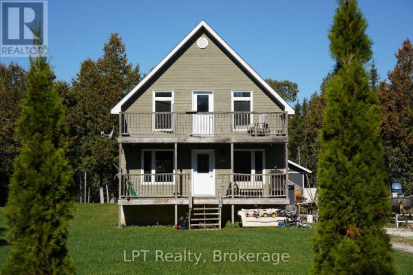Front view of a two-story house with green wood siding, multiple windows, and railings on the decks. - 43 Henwood Street, Northern Bruce Peninsula