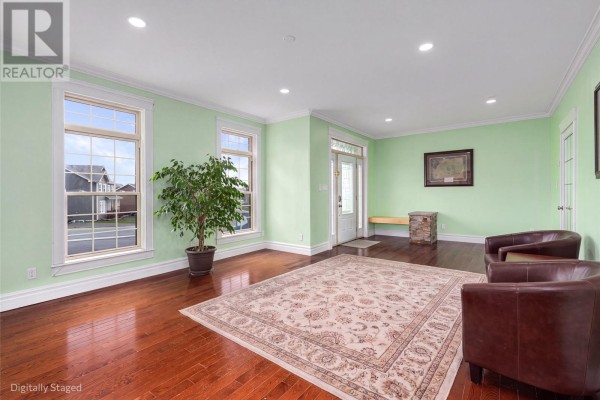 Living room with light green walls, hardwood floors, a sofa, and large windows overlooking the street. - 43 Kirkston Avenue, Conception Bay South