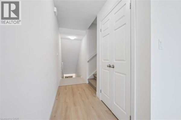 Interior hallway with light wood flooring, white walls, and double doors. - 43 Lomond Lane, Kitchener