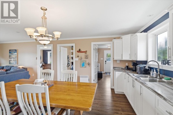 Kitchen and dining area with white cabinets, wooden table, doors leading to other rooms. - 43 Munroe's Pond, Lewisporte