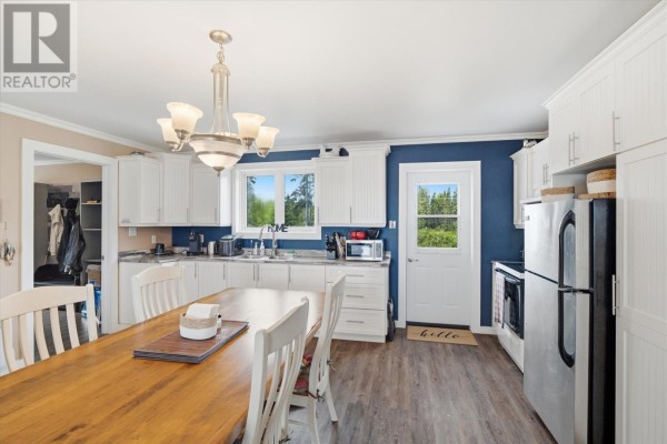 Kitchen with white cabinetry, stainless steel appliances, dining table, and a back door. - 43 Munroe's Pond, Lewisporte