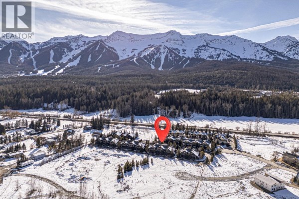 Aerial view of townhome complex surrounded by trees and mountains. - 43 Rivermount Place Unit# 104d, Fernie