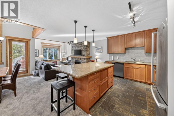 Kitchen island with granite countertop, wood cabinets, and stainless steel appliances. - 43 Rivermount Place Unit# 104d, Fernie