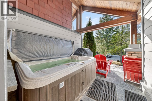 Covered patio with hot tub, red chairs, and mountain view. - 43 Rivermount Place Unit# 104d, Fernie