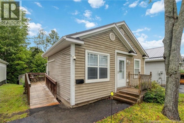 Side view of a beige wood-sided bungalow with a ramp leading to a small deck. - 43 Sequoia Drive, Moncton