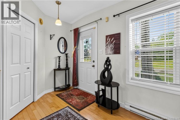 Entryway with white double doors, light wood floors, a console table, and a window. - 43 Sequoia Drive, Moncton