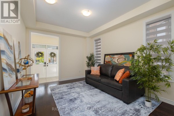 Living room with a dark leather sofa, grey patterned rug, and dark wood floors. - 43 Vickery Street, Whitby