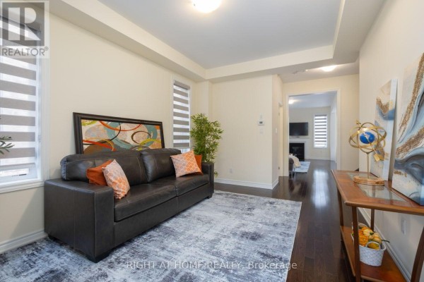 Living room with sofa, rug, console table, and doorway to hallway with staircase. - 43 Vickery Street, Whitby