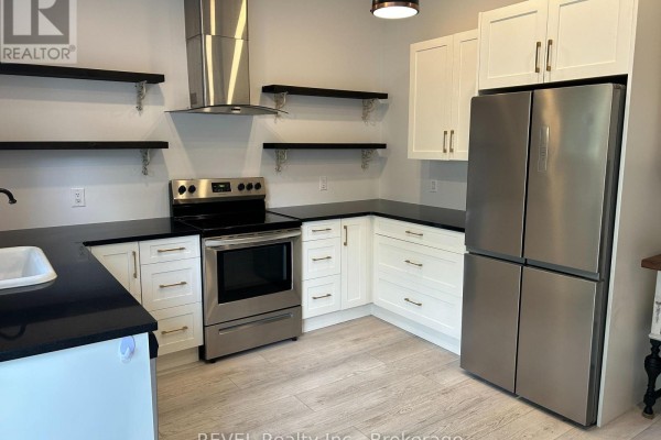 Kitchen with white cabinets, stainless steel appliances, and black countertops. - 43 Wiley Street, St  Catharines