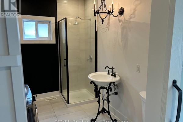 Bathroom with a walk-in shower, a pedestal sink, and a decorative chandelier. - 43 Wiley Street, St  Catharines