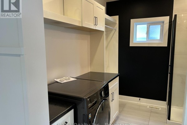 Laundry area with a washing machine, dark countertops, and white cabinets. - 43 Wiley Street, St  Catharines