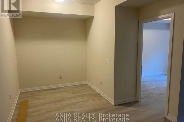Empty room with light beige walls, light wood laminate flooring, and an open doorway. - 430 - 3270 Sheppard Avenue E, Toronto