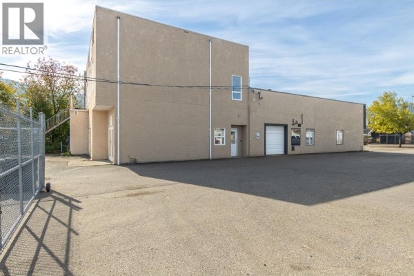 Rear exterior view of the commercial building with a large roll-up door. - 430 7 Street Sw, Salmon Arm