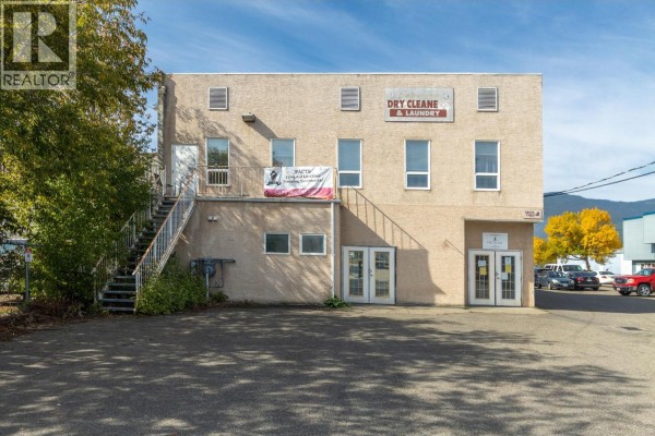 Rear exterior of commercial building with double doors, windows, and metal stairs. - 430 7 Street Sw, Salmon Arm