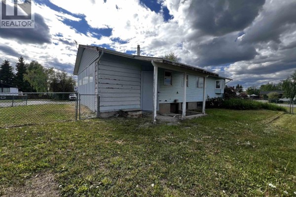 Compact kitchen with beige cabinets, white appliances, and a window overlooking the yard. - 430 Endako Place, Fraser Lake