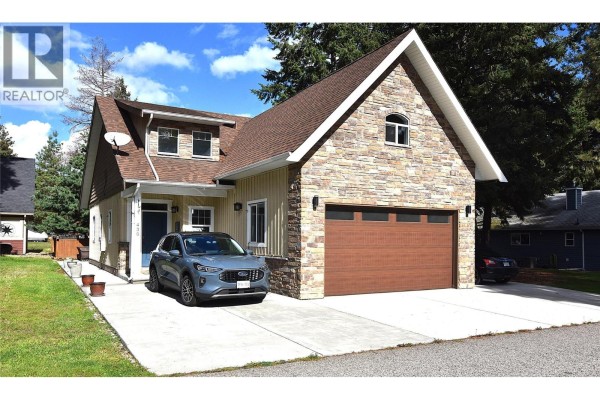 Front exterior view of a house with stone facade, brown garage door, and parked vehicles. - 430 Hummingbird Avenue, Vernon