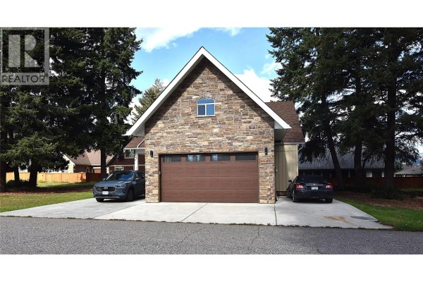 Front elevation of a house featuring a prominent stone facade and a wide garage door. - 430 Hummingbird Avenue, Vernon