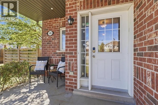 Close-up of the covered front porch with seating and the white front door. - 430 Mountain Laurel Crescent, Kitchener