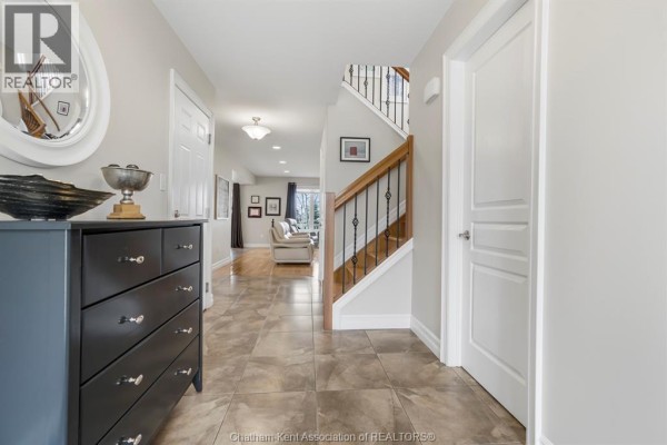 Wide view of the interior foyer with tan tiled floors, white doors, a dark console table, and double glass front doors. - 430 Twilight Trail, Chatham