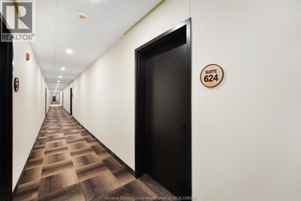 Interior hallway with beige walls, a patterned carpet, and doors to various suites. - 4300 Laurier Parkway Unit# 624, Lasalle