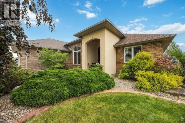 Front entrance of a house with a stucco arched entryway, brick exterior, and manicured landscaping. - 4303 Garden Crescent, Petrolia
